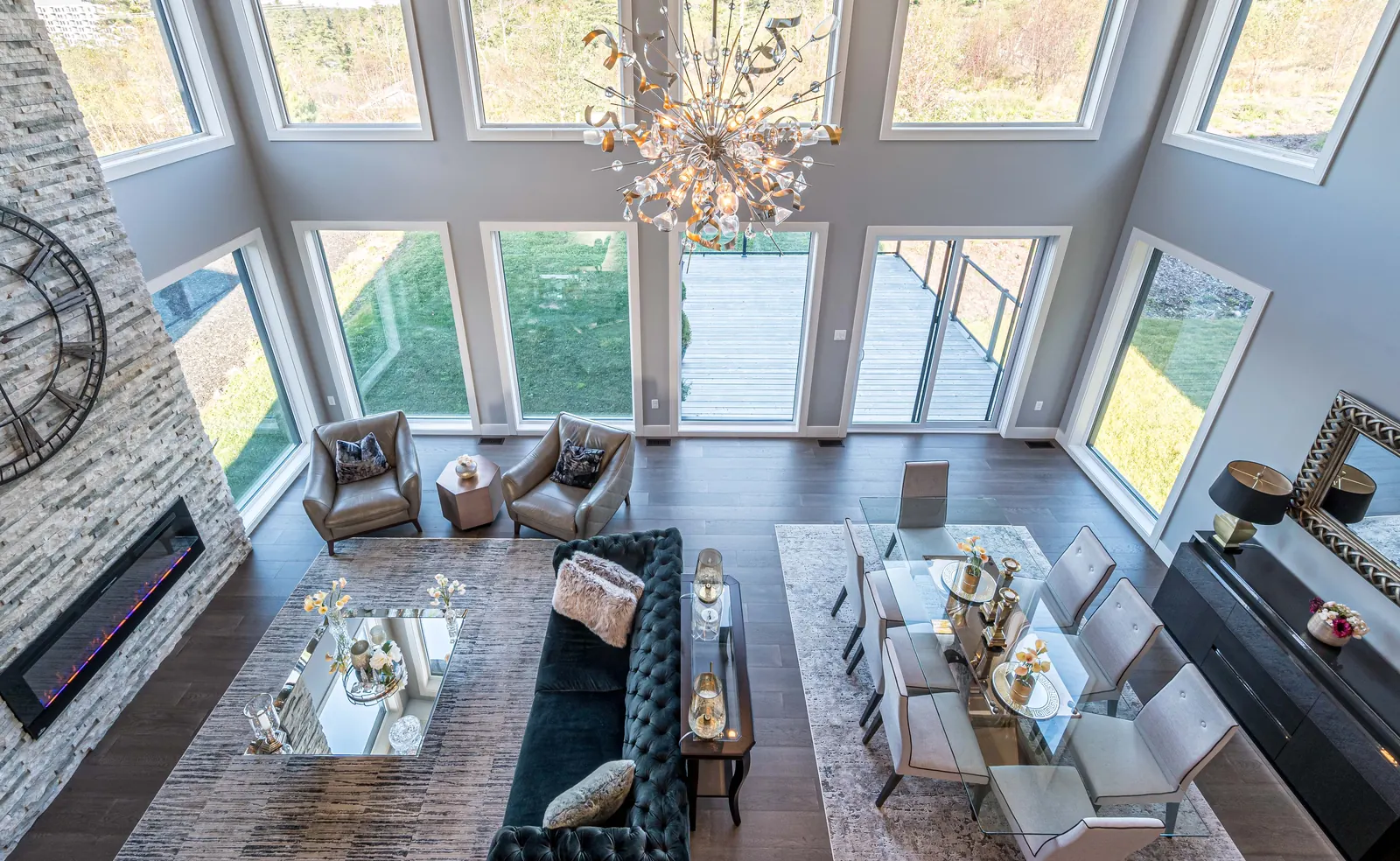 Double-height Halifax great room with a stone fireplace, a wall of windows and layered seating, designed by MAD Design Interiors