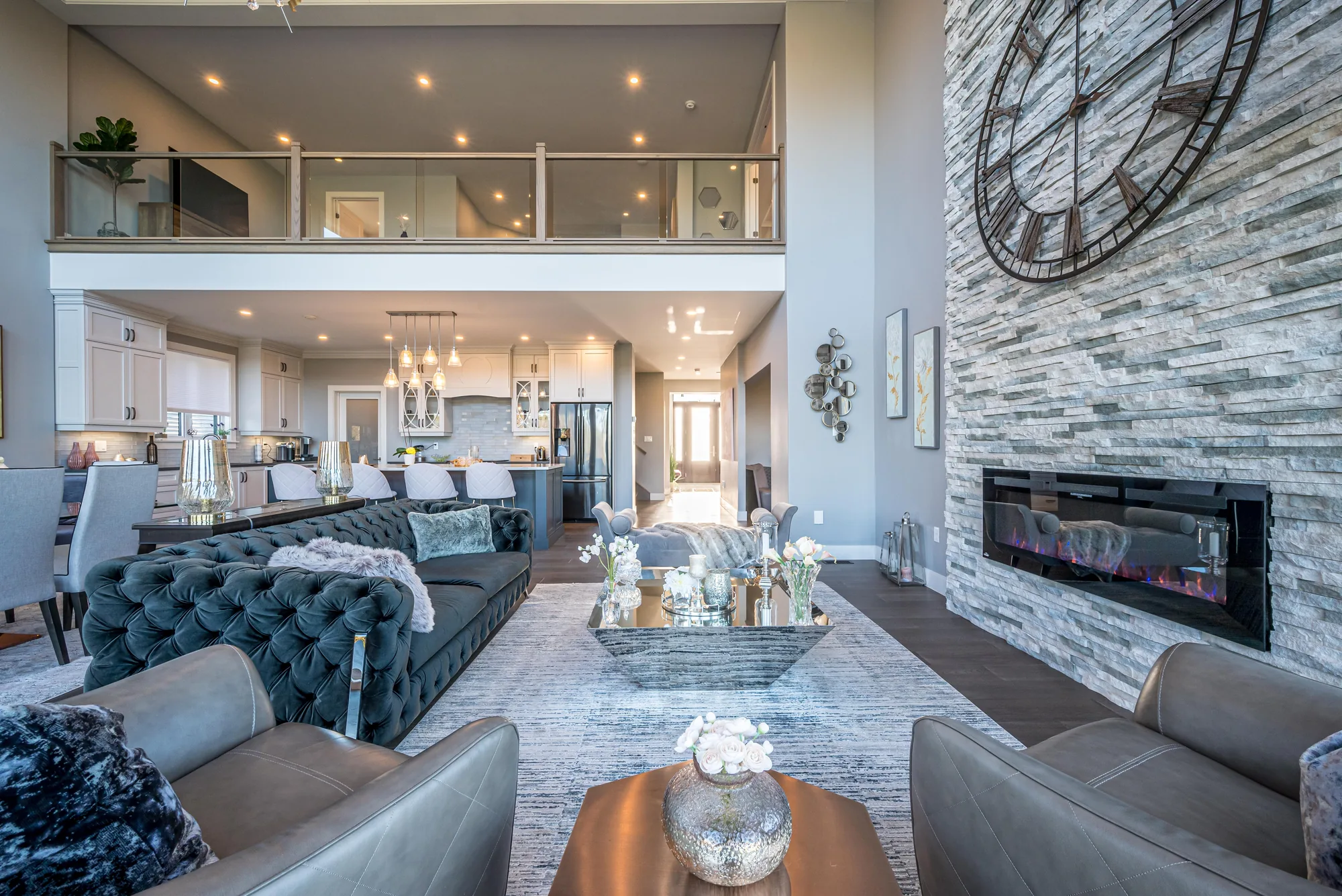 Open-plan great room with a linear fireplace, mezzanine overlook, and layered seating, designed by MAD Design Interiors in Halifax