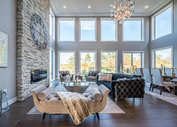 Double-height Halifax living space with a stone fireplace and a full wall of windows, designed by MAD Design Interiors