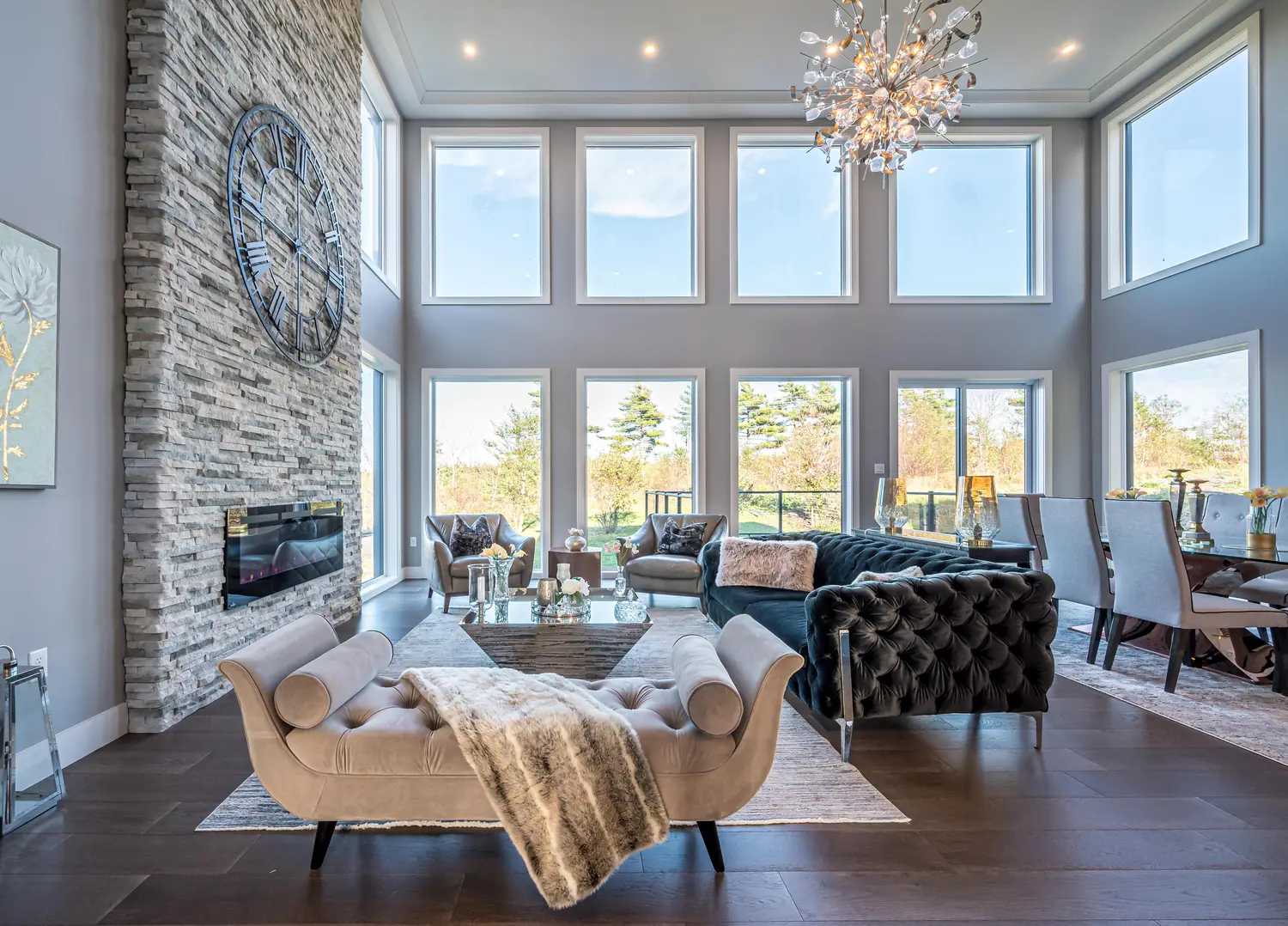 Double-height Halifax living space with a stone fireplace and a full wall of windows, designed by MAD Design Interiors